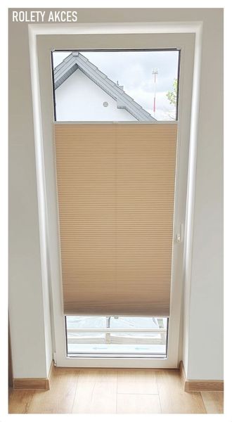 Jasnobrązowe rolety plisowane zamontowane na wysokim oknie.